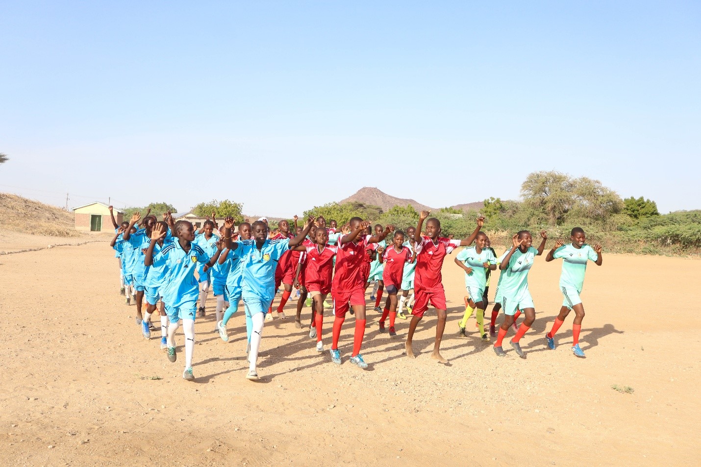Desert Roses teams warming up together on a football field in Turkana